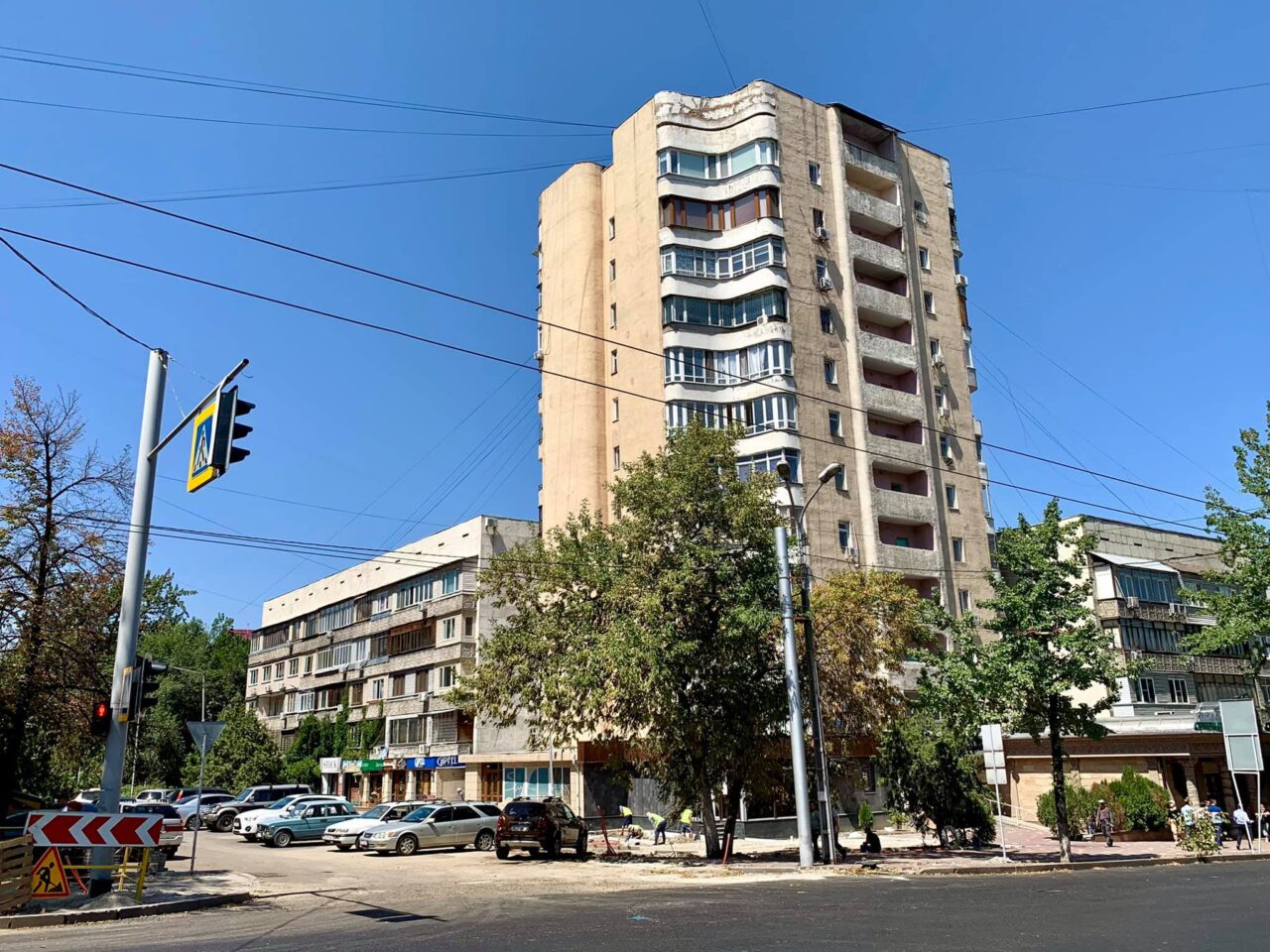 Az árnyas Dostyk sugárút, rajta jellegzetes szovjet lakóépülettel